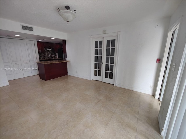 616 Executive Center Dr Unit 107, West Palm Beach, FL 33401 - unfurnished living room with french doors, baseboards, and a textured ceiling