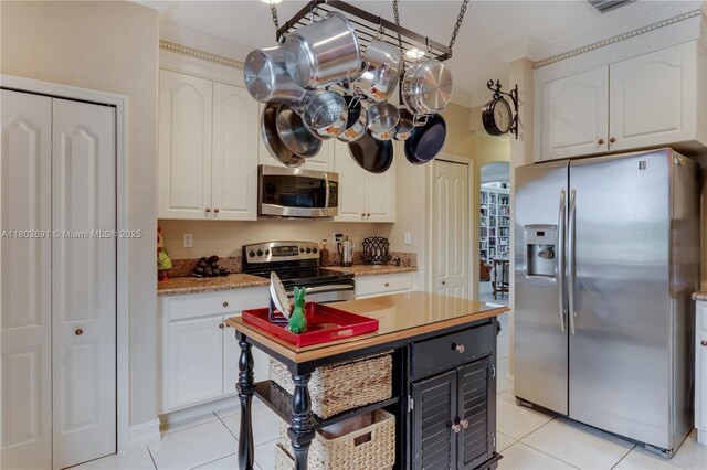 9248 SW 209th Ter, Cutler Bay, FL 33189 - kitchen with stainless steel appliances, light tile patterned floors, white cabinets, a kitchen island, and crown molding