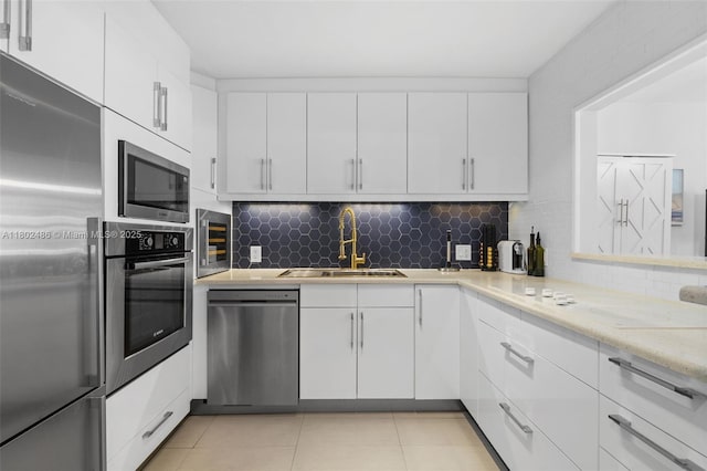 1228 W Ave Unit 704, Miami Beach, FL 33139 - kitchen featuring stainless steel appliances, a sink, white cabinetry, and decorative backsplash