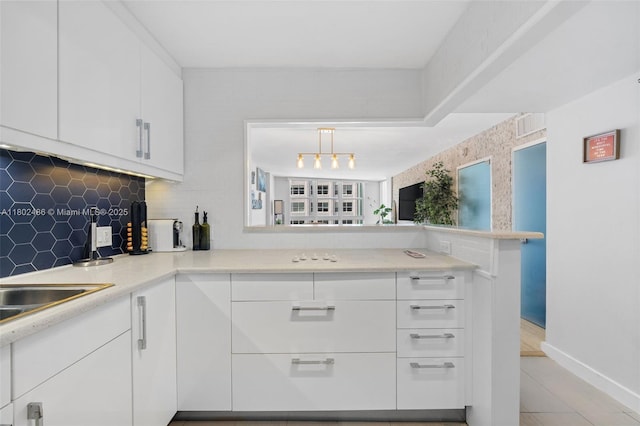 1228 W Ave Unit 704, Miami Beach, FL 33139 - kitchen with backsplash, light countertops, white cabinetry, light tile patterned floors, and baseboards