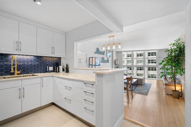 1228 W Ave Unit 704, Miami Beach, FL 33139 - kitchen with a sink, a peninsula, tasteful backsplash, and white cabinets