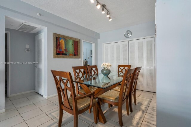 5601 Collins Ave Unit 615, Miami Beach, FL 33140 - dining space featuring light tile patterned flooring, rail lighting, a textured ceiling, and baseboards