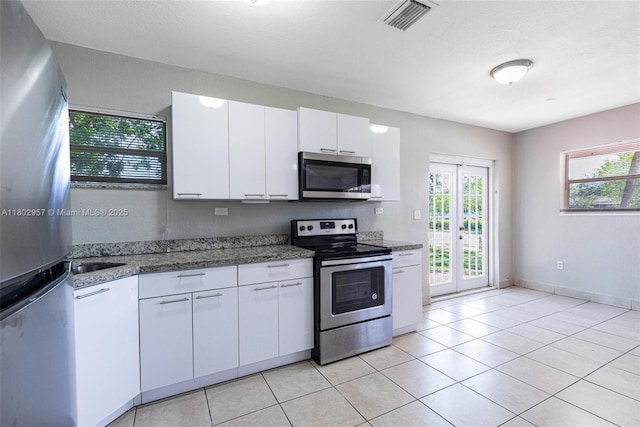 20740 NE 13th Ct, Miami, FL 33179 - kitchen featuring stainless steel appliances, white cabinets, light stone countertops, and light tile patterned floors