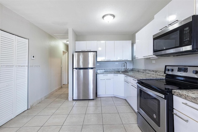 20740 NE 13th Ct, Miami, FL 33179 - kitchen featuring stainless steel appliances, a sink, white cabinets, light stone counters, and light tile patterned floors