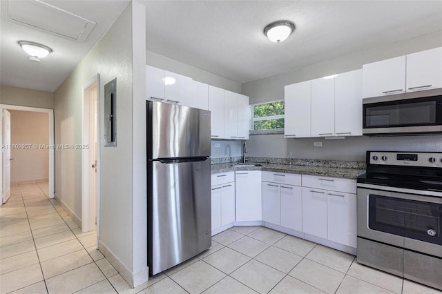 20740 NE 13th Ct, Miami, FL 33179 - kitchen featuring stainless steel appliances, light tile patterned flooring, white cabinets, and a sink