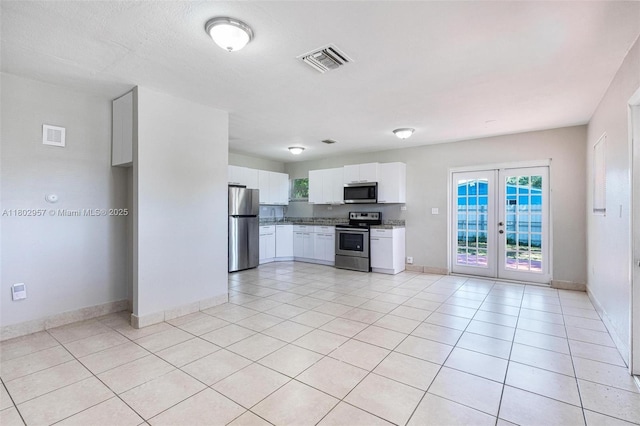 20740 NE 13th Ct, Miami, FL 33179 - kitchen featuring appliances with stainless steel finishes, french doors, white cabinetry, baseboards, and light tile patterned flooring
