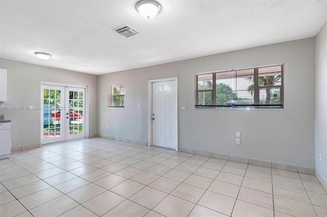 20740 NE 13th Ct, Miami, FL 33179 - spare room featuring french doors, healthy amount of natural light, light tile patterned floors, baseboards, and a textured ceiling