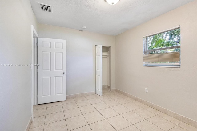 20740 NE 13th Ct, Miami, FL 33179 - unfurnished bedroom with light tile patterned flooring, a closet, baseboards, and a textured ceiling