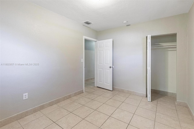 20740 NE 13th Ct, Miami, FL 33179 - unfurnished bedroom with light tile patterned flooring, a closet, baseboards, and a textured ceiling