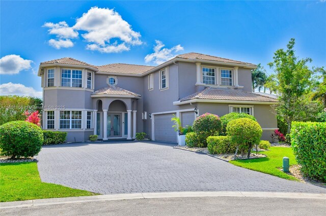 5081 NW 120th Ave, Coral Springs, FL 33076 - mediterranean / spanish-style home featuring a tiled roof, a garage, stucco siding, decorative driveway, and a front yard