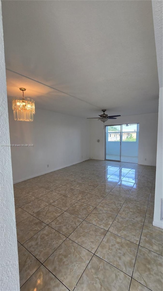 spare room with a chandelier, ceiling fan, and light tile patterned flooring