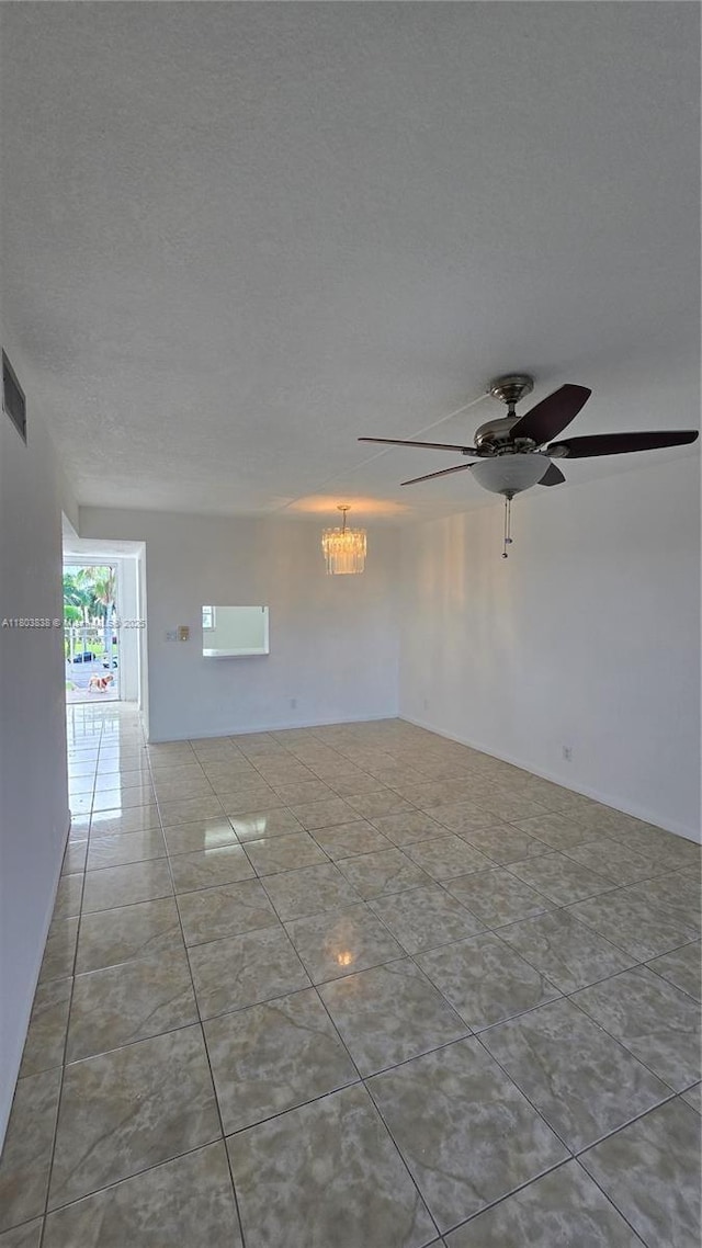 spare room with ceiling fan, a textured ceiling, a chandelier, and tile patterned floors