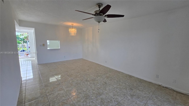 spare room with a chandelier, ceiling fan, and light tile patterned floors