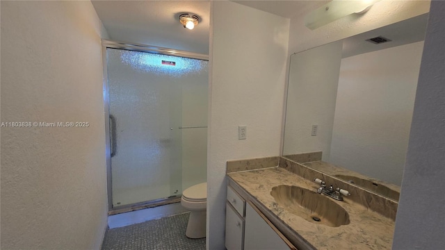 bathroom featuring a stall shower, toilet, a textured wall, vanity, and tile patterned flooring