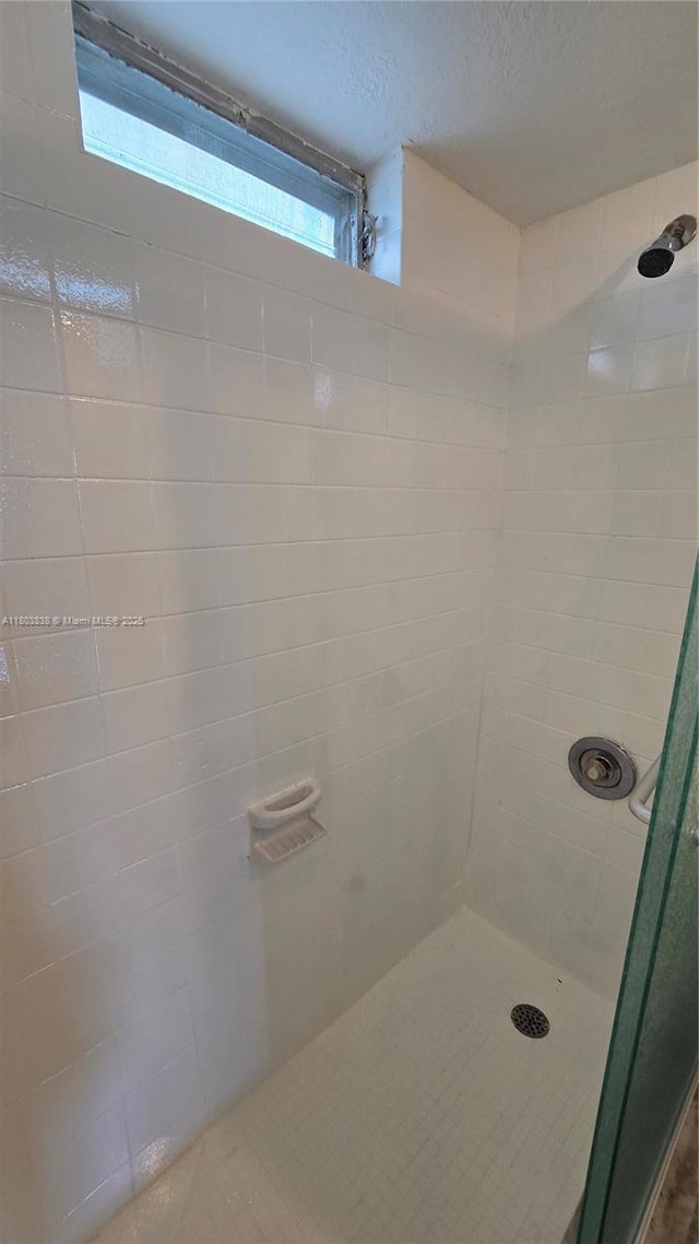 full bathroom with tiled shower and a textured ceiling