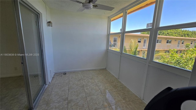 unfurnished sunroom with ceiling fan, tile patterned floors, and a textured ceiling