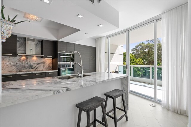 2127 Brickell Ave Unit 502, Miami, FL 33129 - kitchen with modern cabinets, wall chimney exhaust hood, a kitchen breakfast bar, a sink, and tasteful backsplash