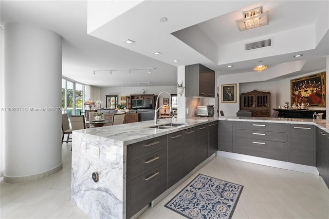 2127 Brickell Ave Unit 502, Miami, FL 33129 - kitchen with a peninsula, a sink, modern cabinets, open floor plan, and light stone counters