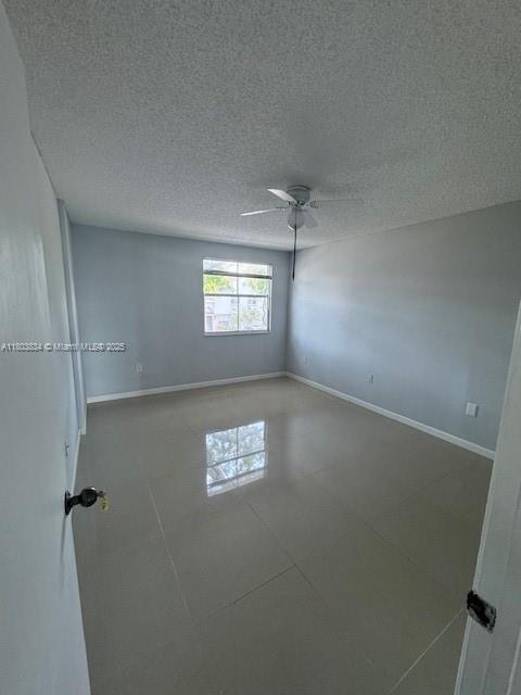 4724 NW 97th Ct Unit 87, Doral, FL 33178 - tiled spare room featuring baseboards, a ceiling fan, and a textured ceiling