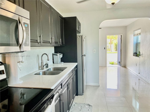 3135 SW 64th Ave, Miami, FL 33155 - kitchen featuring a sink, appliances with stainless steel finishes, light tile patterned floors, baseboards, and arched walkways