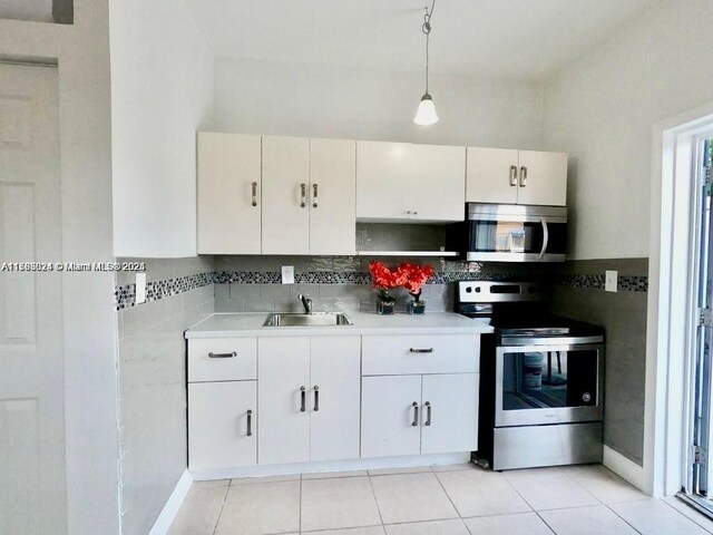 3135 SW 64th Ave, Miami, FL 33155 - kitchen featuring appliances with stainless steel finishes, a sink, light countertops, pendant lighting, and white cabinetry