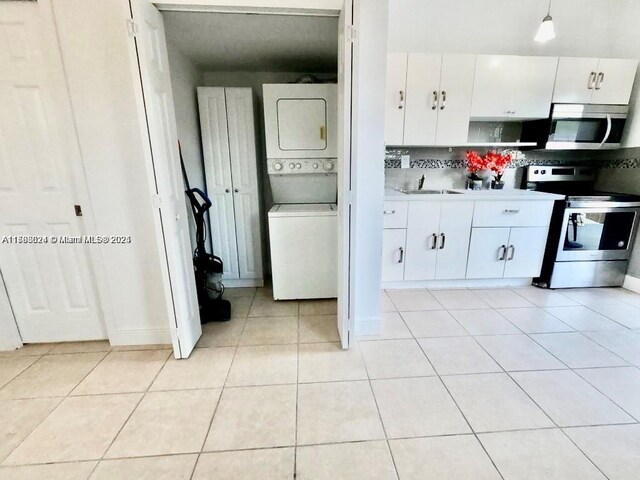 3135 SW 64th Ave, Miami, FL 33155 - kitchen with stainless steel appliances, stacked washer / drying machine, a sink, white cabinets, and light countertops