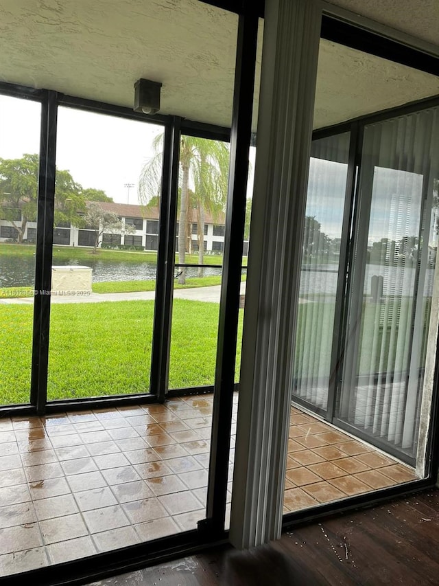 203 Lake Pointe Dr Unit 108, Oakland Park, FL 33309 - doorway to outside with a water view, plenty of natural light, a textured ceiling, and expansive windows
