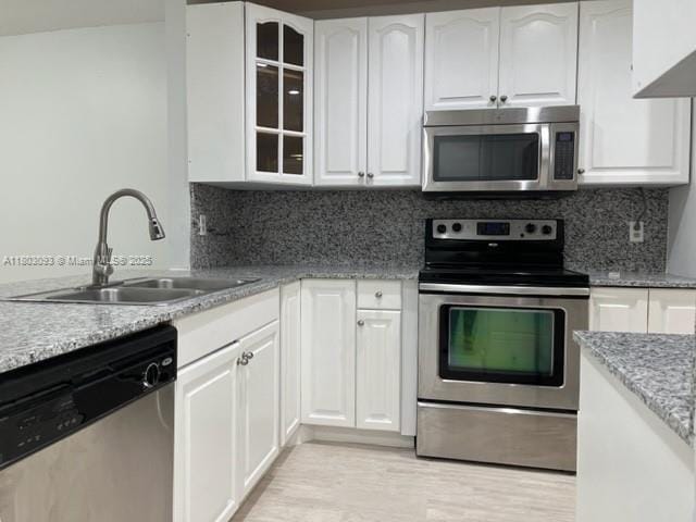 447 Lakeview Dr Unit 5, Weston, FL 33326 - kitchen with stainless steel appliances, a sink, glass insert cabinets, white cabinetry, and light stone countertops