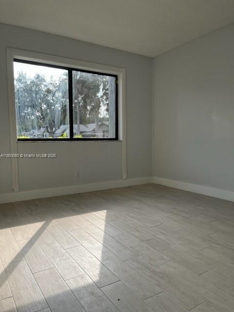 447 Lakeview Dr Unit 5, Weston, FL 33326 - empty room with plenty of natural light, baseboards, and light wood-style flooring