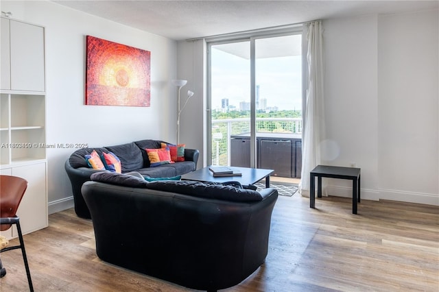 living room with light wood-style flooring, floor to ceiling windows, a city view, and baseboards