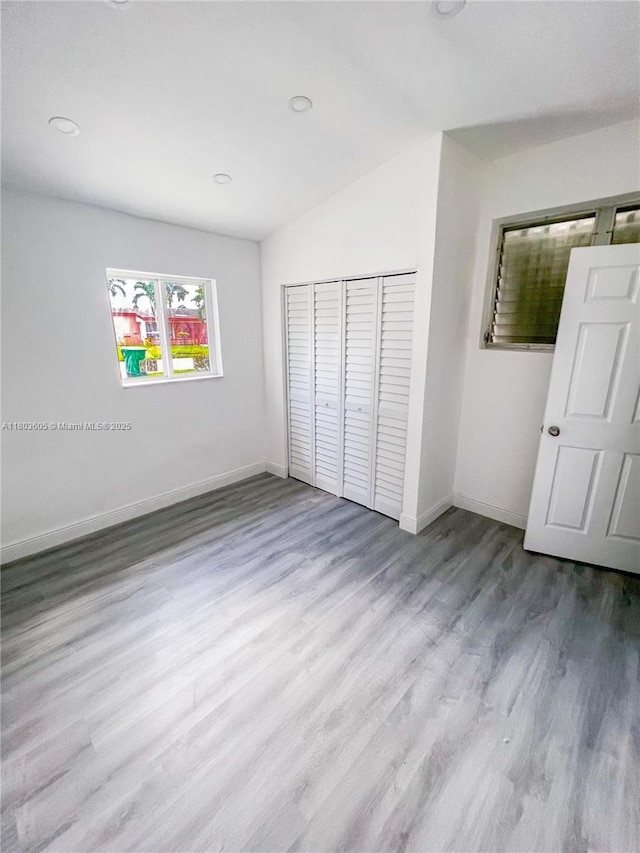 7917 Kismet St, Miramar, FL 33023 - unfurnished bedroom with wood finished floors, baseboards, a closet, and lofted ceiling
