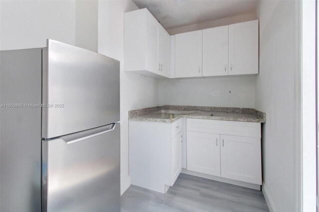 7917 Kismet St, Miramar, FL 33023 - kitchen with freestanding refrigerator, white cabinets, and light wood finished floors
