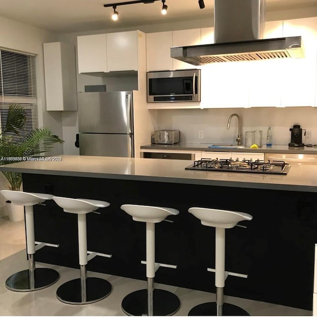 1618 Michigan Ave Unit 26, Miami Beach, FL 33139 - kitchen with stainless steel appliances, wall chimney exhaust hood, a breakfast bar, and white cabinetry