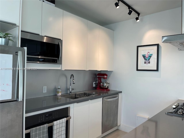 1618 Michigan Ave Unit 26, Miami Beach, FL 33139 - kitchen featuring appliances with stainless steel finishes, a sink, track lighting, white cabinets, and dark countertops