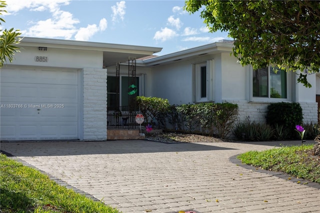 8851 Byron Ave, Surfside, FL 33154 - view of front of house with a garage, decorative driveway, brick siding, and stucco siding