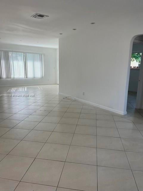8851 Byron Ave, Surfside, FL 33154 - unfurnished room with arched walkways, light tile patterned floors, healthy amount of natural light, and baseboards