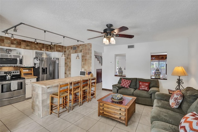 16465 NE 26th Ave Unit 18, North Miami Beach, FL 33160 - living room with rail lighting, ceiling fan, a textured ceiling, and light tile patterned floors