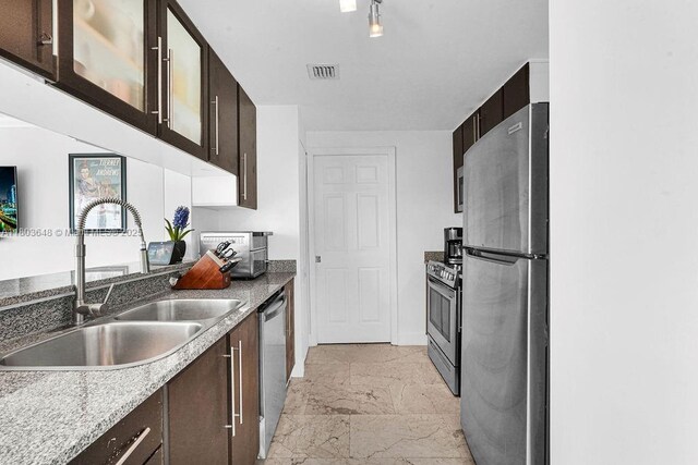 275 NE 18th St Unit 306, Miami, FL 33132 - kitchen featuring stainless steel appliances, light marble finish floors, dark brown cabinets, and glass insert cabinets