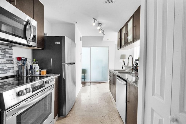 kitchen with stainless steel appliances, a sink, dark brown cabinets, and tasteful backsplash
