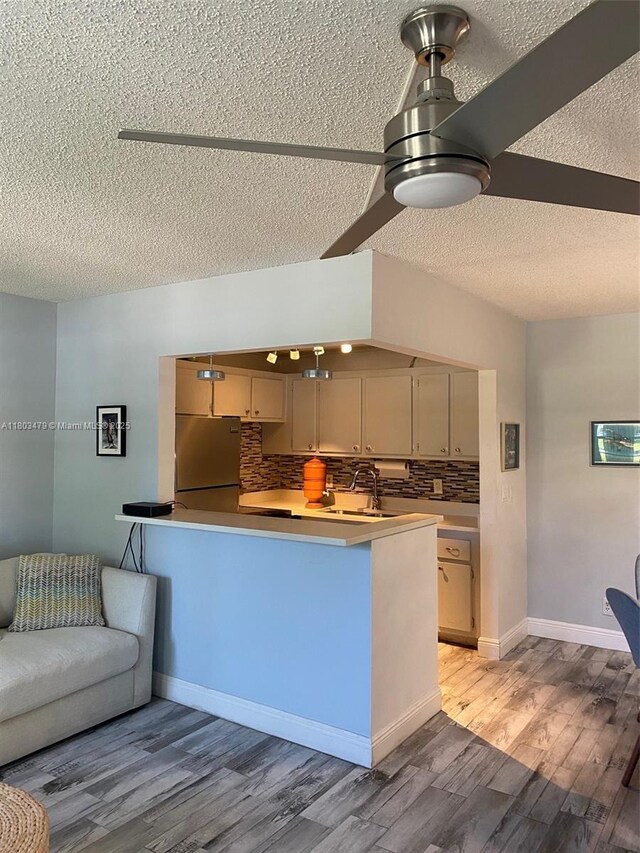 172 Prescott I 172, Deerfield Beach, FL 33442 - kitchen featuring freestanding refrigerator, a textured ceiling, decorative backsplash, light wood finished floors, and a peninsula
