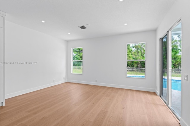 empty room with light wood-style flooring, recessed lighting, plenty of natural light, and baseboards