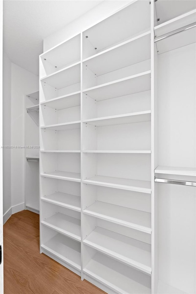 walk in closet with wood finished floors