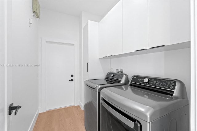 laundry area with cabinet space, light wood-style floors, washing machine and dryer, and baseboards