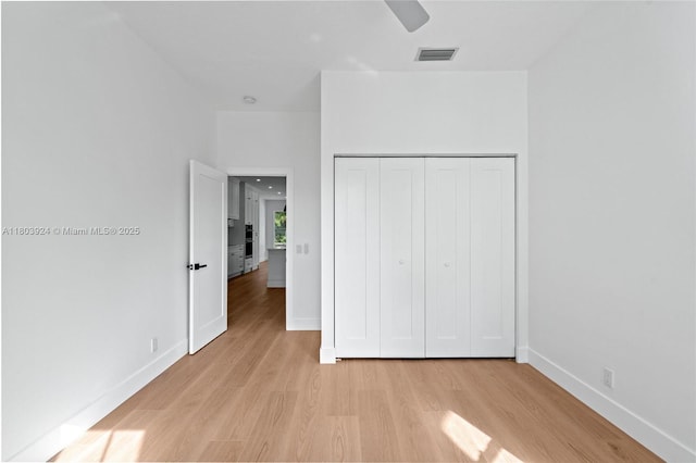 unfurnished bedroom featuring light wood-style floors, baseboards, a closet, and a ceiling fan
