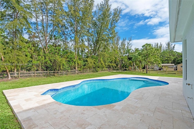 view of swimming pool featuring a patio and view of scattered trees