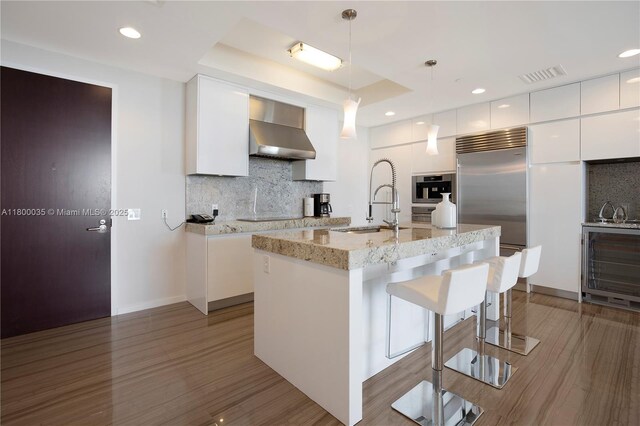 9705 Collins Ave Unit 1805N, Bal Harbour, FL 33154 - kitchen featuring wall chimney exhaust hood, modern cabinets, a sink, backsplash, and dark wood-type flooring