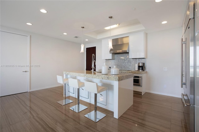 9705 Collins Ave Unit 1805N, Bal Harbour, FL 33154 - kitchen with wall chimney range hood, oven, tasteful backsplash, white cabinetry, and modern cabinets