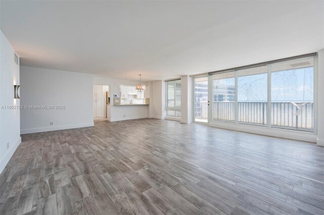4280 Galt Ocean Dr Unit 23A, Fort Lauderdale, FL 33308 - unfurnished living room featuring wood finished floors, baseboards, and a chandelier