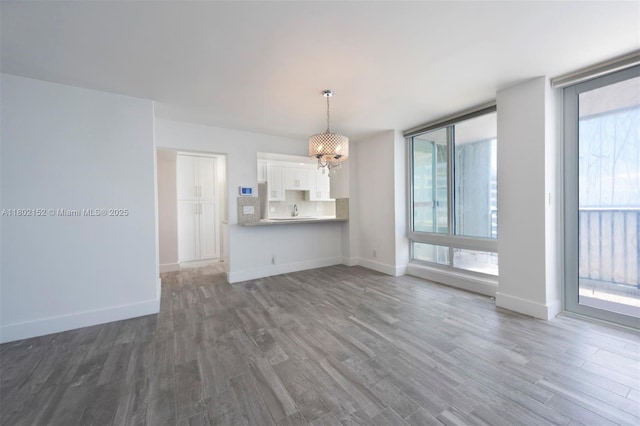 4280 Galt Ocean Dr Unit 23A, Fort Lauderdale, FL 33308 - unfurnished living room featuring a chandelier, wood finished floors, baseboards, and a sink
