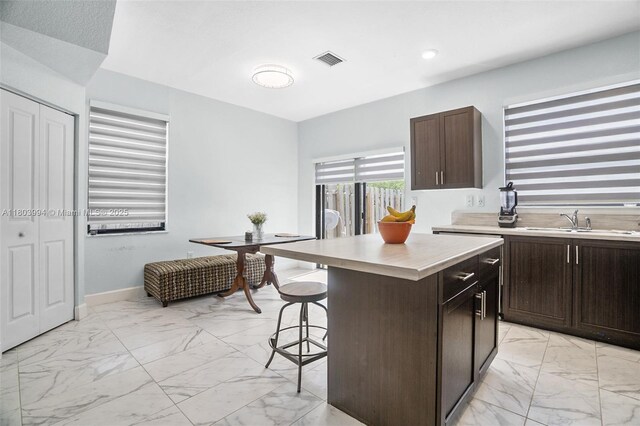 21408 NE 2nd Path, Miami, FL 33179 - kitchen featuring light marble finish floors, a kitchen bar, light countertops, a sink, and a center island